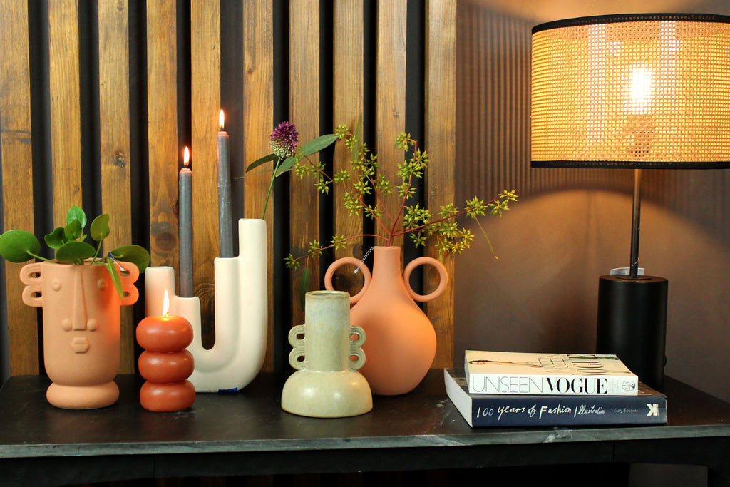 marmeren sidetable met vazen in verschillende kleuren en vormen en een rotan tafellamp